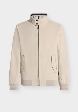 Beige jakke med høy krage, glidelåslukking, to sidelommer, ribbestrikkede mansjetter og kant, med stripete innerfôr.