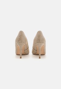 Scarpe con tacco alto beige in tessuto texturizzato rivestito di piccoli strass, punta affusolata e sottile tacco a spillo.
