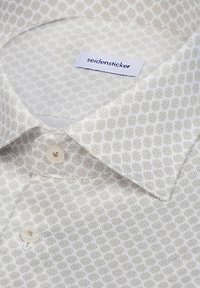 Chemise blanche avec un motif géométrique étoile gris subtil, deux boutons blancs et une étiquette "seidensticker" à l'intérieur du col.