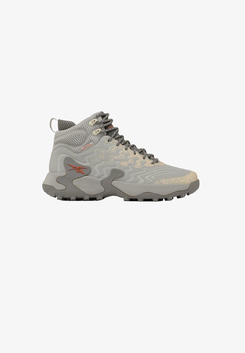 High-top gray and beige hiking shoe with wavy textured sole, mesh upper, black laces, and orange logo on side.