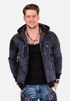 Marineblaues Kapuzenshirt mit strukturiertem Stoff und schwarzen gesteppte Akzenten, ausgestattet mit Reißverschlusstaschen vorne und gerippten Bündchen.