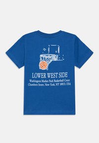 Blå bomull t-skjorte med et basketballgrafikk og teksten "LOWER WEST SIDE," med en kurv- og balldesign i hvitt og oransje.