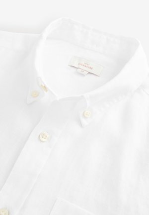 White linen button-up shirt with a pointed collar, featuring cream buttons, textured fabric, and a left chest pocket. Tag visible inside.