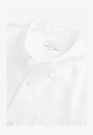 White linen button-up shirt with a pointed collar, featuring cream buttons, textured fabric, and a left chest pocket. Tag visible inside.