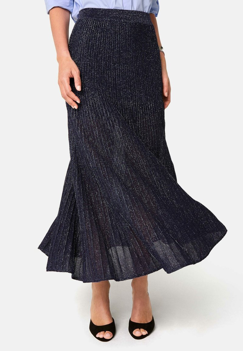 Marineblaue plissierte Midi-Rock mit metallic Faden, aus strukturierter Stoff, mit einem ausgestellten Saum, kombiniert mit schwarzen, offenen Absatzschuhen.