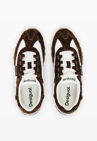 Sneakers din suede maro cu panouri albe din plasă, șireturi rotunde, accente texturate asemănătoare blănii și talpa din cauciuc. Numele brandului "Desigual" este vizibil în interior.