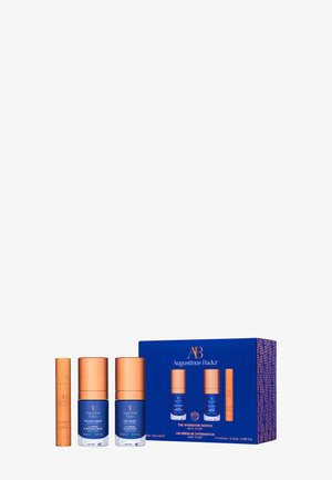 Augustinus Bader Hautpflege-Set mit blauen und kupferfarbenen Flaschen und einer blauen Box mit der Aufschrift „The Hydration Heroes“ auf weißem Hintergrund.
