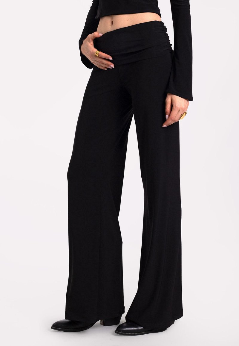 I pantaloni neri a gamba larga presentano un cintura arricciata e un tessuto liscio e leggero. Il design offre una silhouette rilassata e una caduta sobria.