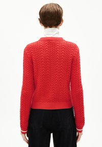 Roter Kabelstrickpullover mit gerippten Bündchen und Saum. Verfügt über kontrastierende weiße Streifen an den Handgelenken, eine taillierte Passform und strukturierte Stoffoberfläche.