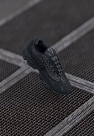 Scarpa da corsa nera con tomaia in mesh e sintetico, caratterizzata da una punta arrotondata, accenti testurizzati e una soletta imbottita. Logo del marchio visibile sul lato.