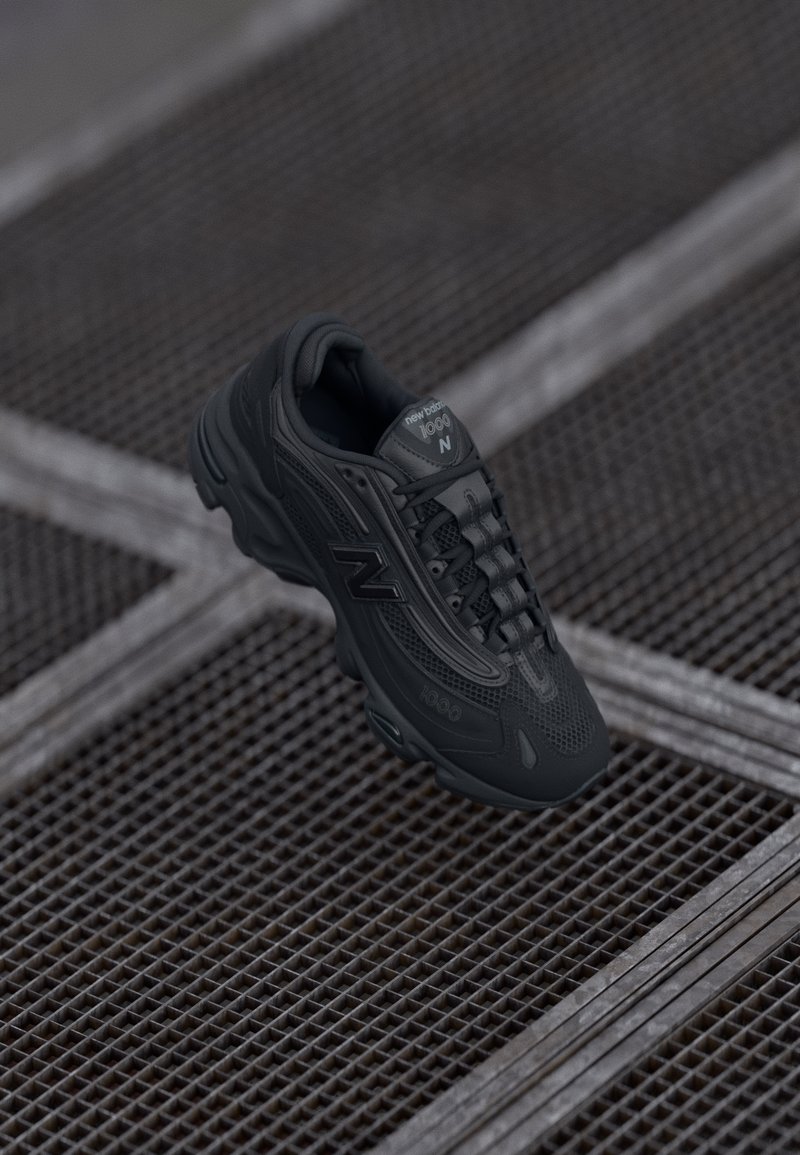 Black running shoe with mesh and synthetic upper, featuring a rounded toe, textured accents, and a cushioned sole. Brand logo visible on side.