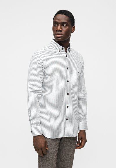 Camisa de botão branca com riscas verticais escuras, com gola, mangas compridas e um bolso no peito. Botões escuros como detalhes.