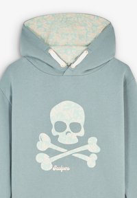 Jasnoniebieska bluza z kapturem z dużym białym wzorem czaszki i skrzyżowanych kości. Wnętrze ma kwiatowy wzór. Zawiera sznurki ściągające i metalowe elementy.
