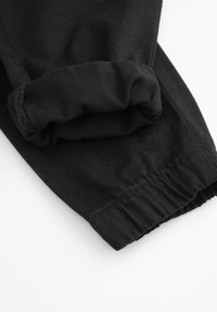 Czarne bawełniane spodnie z zebranym mankietem z elastycznym wykończeniem, gładką teksturą i zszytymi szwem.