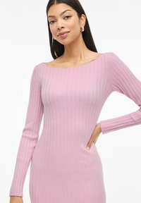 Dugno megztas, ilgomis rankovėmis šviesiai rožinės spalvos suknelė su valtine apykakle. Minkšta tekstūra, prigludęs siluetas ir subtili briaunelių variacija.