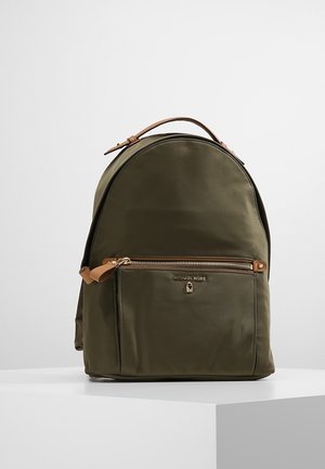 Plecak oliwkowozielony z przednią kieszenią na zamek, rączką z jasnobrązowej skóry oraz złotym logo Michael Kors na przedniej kieszeni.