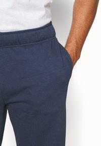 Navy blauwe joggerbroeken, gemaakt van zacht katoen. Voorzien van een elastische tailleband en zijzakken, met een gladde textuur en een ontspannen pasvorm.