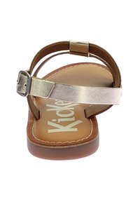 Sandal in pelle marrone con una fascia metallica argentata. Presenta una soletta leggermente sollevata e un design cucito sulla suola. Chiusura con fibbia.