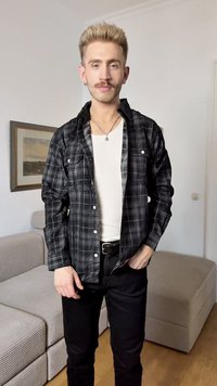 Camisa de flanela xadrez em preto e branco com mangas longas, frente com botões e dois bolsos no peito, usada sobre uma camisa branca e calças pretas.