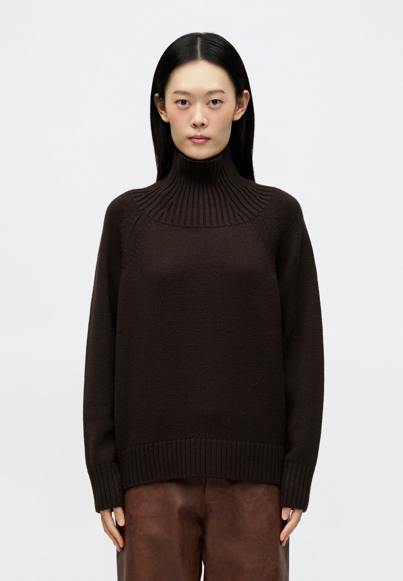 Maglione a collo alto marrone scuro con texture a coste, caratterizzato da una vestibilità rilassata, spalle cadenti e ampi rib cuff e orlo.
