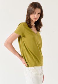 Groene V-hals t-shirt met korte mouwen, gemaakt van zachte stof, met een ontspannen fit en subtiele zijnaaddetails.