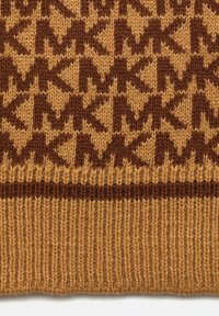 Tissu tricoté marron et beige avec des motifs géométriques d'étoiles et de diamants au-dessus d'un ourlet côtelé.