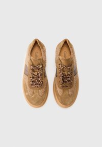 Brown suede sneakers with fuzzy accents, leopard print laces, and a rubber sole. Features two dark brown stripes on the sides.
