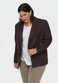 Pruun faux suede bleiser, mille on klappkrae ja üksik nupp. Kandub valge T-särgi peal, koos beeži leopardimustriga retuusidega.