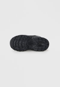 Semelle de sneaker noire avec du caoutchouc texturé, plusieurs motifs de semelle et un logo central. Durable avec un design solide et courbé.