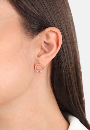 Pendiente de aro en oro rosa con un diseño circular que presenta una fila de pequeñas gemas transparentes a lo largo del borde inferior. Textura suave.
