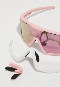 Rosa Sportsonnenbrille mit lila verlaufenden Gläsern, ausgestattet mit einem leichten Gestell und austauschbaren weißen und schwarzen Nasenpolstern.