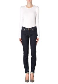 Top blanco de manga larga combinado con jeans skinny de mezclilla oscura. Los jeans presentan bolsillos estándar y puños enrollados, complementados por tacones altos grises.