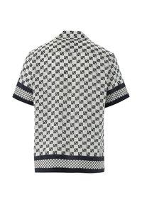Camicetta a maniche corte con un motivo geometrico in bianco e nero, rifiniture nere a contrasto e un design cropped con orlo a scacchi.