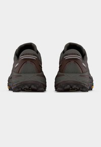 Ζευγάρι σκούρων καφέ παπουτσιών για τρέξιμο σε μονοπάτια με παχιά πέλματα με αυλακώσεις, πίσω όψη που δείχνει μαξιλαρωμένους γιακάδες και ανακλαστικές λεπτομέρειες.