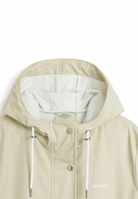 Beige sadejakke med hette i hvit fleece, justerbare snor, trykknapplukking og en logo på forsiden.