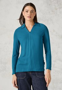 Tiefblaues Langarmshirt mit V-Ausschnitt und Kragen, aus einem glatten Stoff gefertigt. Verfügt über einen geraden Saum und diskrete seitliche Schlitze für Bewegungsfreiheit.