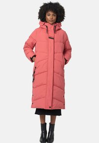 Lang, gewatteerde roze jas met een capuchon, zwarte accenten, diagonale stiksels, zijzakken en drukknopen. Draagt over een zwarte trui en laarzen.