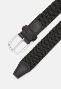 Cinturón elástico tejido en verde oscuro con hebilla y punta de cuero. Presenta una hebilla de metal plateado y un diseño trenzado. Material duradero y flexible.