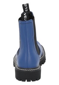 Botín de cuero azul con paneles laterales elásticos negros, una lengüeta en la parte trasera y una suela negra robusta, con acentos de costura blanca.