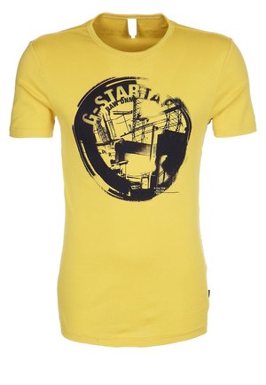 Żółta koszulka z krótkim rękawem z czarnym okrągłym nadrukiem przedstawiającym konstrukcje przemysłowe oraz częściowym napisem "G-STAR RAW" na przodzie.