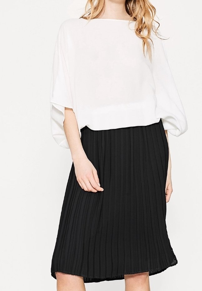 Top bianco, dal taglio morbido con una scollatura ampia abbinato a una gonna midi plissettata nera. Tessuto morbido, design fluido e motivo testurizzato.