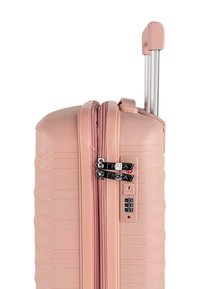 Maleta rígida rosa resistente con textura acanalada, doble cremallera, cerradura de combinación y asa extensible plateada.