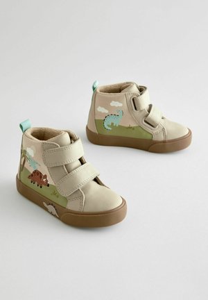 Beige nahkakorkokengät, joissa on kaksi tarranauhaa, ja joissa on dinosaurusteemoja sinisessä ja ruskeassa, sekä vihreitä yksityiskohtia sivuilla.