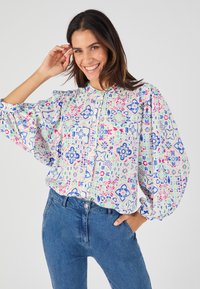 Blusa a manica lunga in tessuto leggero con un motivo geometrico multicolore che presenta tonalità di rosa, blu e verde. Chiusura con bottoni sul davanti.