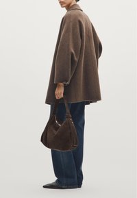 Brown wool coat with oversized sleeves, dark blue jeans, and a brown suede shoulder bag. Black pointed shoes complete the look.
