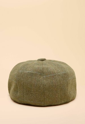 Žalia tvīdo kepurė su apvalia forma ir plokščiu viršumi. Turi zuikio kaulų raštą ir subtilių raudonų bei mėlynų akcentų. Minkšta tekstūra.