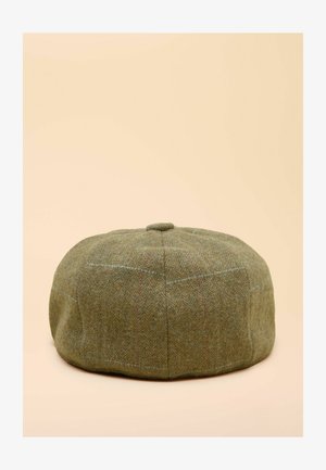 Roheline tweedist nokamüts ümarate joonte ja lameda pealiskihiga. Omab kalasaba mustrit ning peeneid punaseid ja siniseid detaile. Pehme tekstuur.