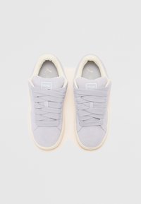 Sneakers in suede grigio chiaro con lacci spessi abbinati, collo imbottito e suola contrastante chiara; presenta una patch con logo sulla linguetta.