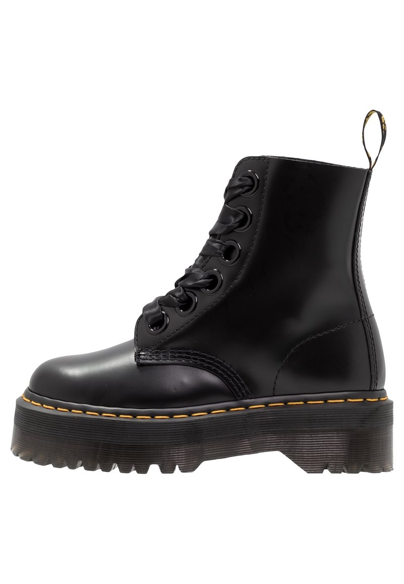 Botte de combat noire en cuir à lacets avec semelle épaisse à rainures et surpiqûres jaunes, vue de côté sur fond blanc.