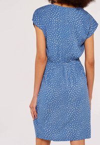 Robe courte à manches courtes bleu avec un motif à pois blancs, taille élastique et une coupe décontractée qui tombe au-dessus du genou. Texture de tissu lisse.